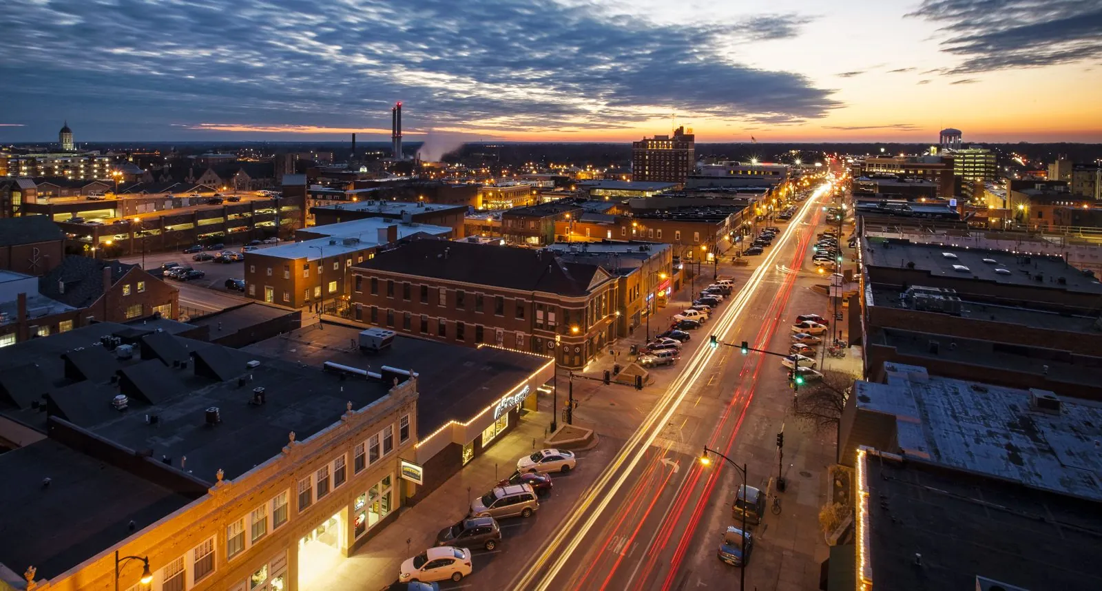 Aerial view of downtown Columbia at sunset, with light trails along the street and Jesse Hall's dome on the skyline